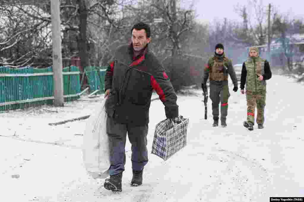 Житель идёт по улице на окраине Авдеевки, за ним &mdash; российские военные. 19 февраля 2024 года. Когда в феврале российские войска приблизились к Авдеевке, остававшиеся в городе жители бежали. Неясно, сколько человек решили остаться &nbsp;
