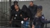 The suspect in the shooting, his head covered by a coat, is escorted by police outside the Vladislav Ribnikar Elementary School in Belgrade on May 3.