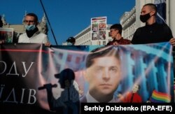 A Hagyományok és rend nevű konzervatív civil mozgalom aktivistái egy gyűlésen Kijev belvárosában 2021. szeptember 16-án egy transzparenst tartanak Zelenszkij elnök arcképével, és felszólítják, hogy döntse el, kit támogat. A tüntetők egy tervezett LMBT-felvonulás ellen tiltakoztak. A háttérben látható tábla szerint az LMBT egyenlő az LDNR-rel, azaz a két szakadár donbászi területtel