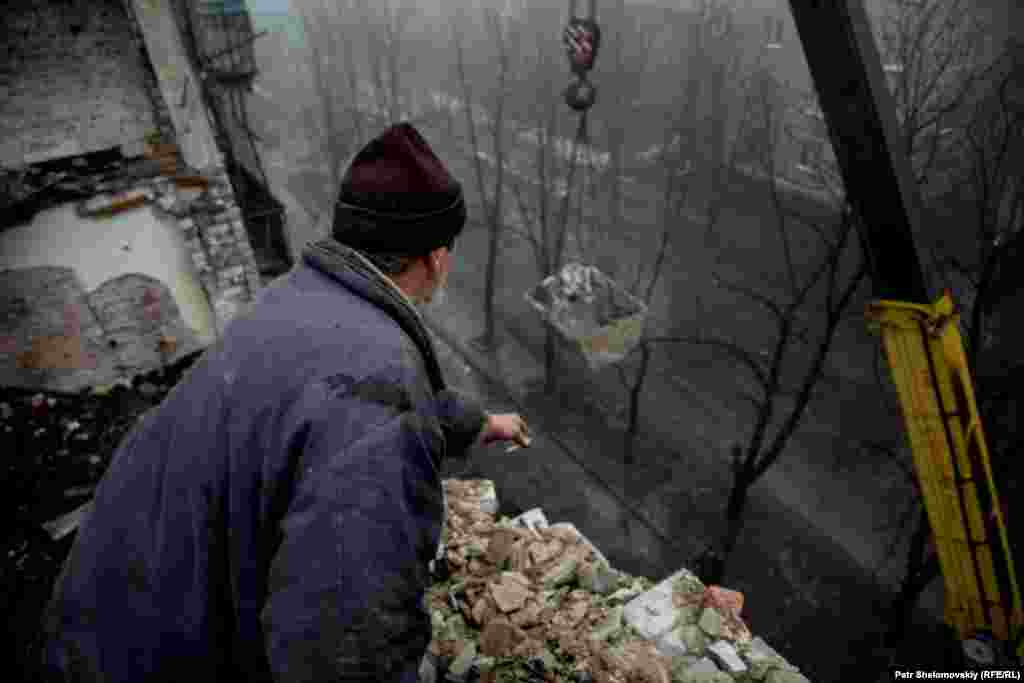 Рабочие разбирают осколки разрушенного здания.