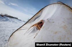 Ертіс өзеніне қатқан мұздың үстінде палатка ішінде отырған балықшы. Ақсу. 22 наурыз 2018 жыл.