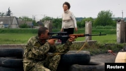 Žena prelazi most pored ruskog militanta, Slavjansk, 15. maj 2014.