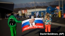 Двама души държат руски флаг с образа на руския президент и с надпис "Благодаря, Путин!". Снимката е от 2014 г.