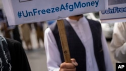 A man holds a banner during a demonstration in Kabul demanding the release of frozen Afghan funds. (file photo)