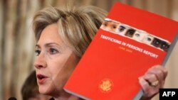 U.S. -- Secretary of State Hillary Clinton holds up the the ninth annual Department of State Trafficking in Persons Report, Washington, DC, 16Jun2009 