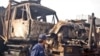 Pakistan -- A private security guard examines burnt trucks, destined for the NATO forces in Afghanistan, after an insurgents' attack at the Fasial terminal in Peshawar, 01Dec2008