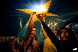 Participanți la un miting de Ziua Europei la București, pe 9 mai, luminează cu telefoanele mobile stelele unui imens steag al Uniunii Europene