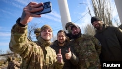Președintele ucrainean Volodimir Zelenski face un selfie cu câțiva militari ucraineni în timpul vizitei surpriză de luni de la Herson, 14 noiembrie 2022.