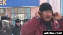 Человек в рабочей спецовке, рядом стоят полицейские. Жанаозен, 16 декабря 2011 года. Скриншот с видеопортала "Стан.кз". 