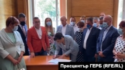 Председателят на парламентарната група на ГЕРБ Даниела Дариткова подписва писмото до другите парламентарни групи пред погледа на свои колеги. Действието се развива в стаята на ГЕРБ в Народното събрание.