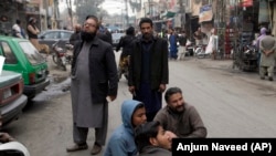 People stand outside their shops after a severe earthquake is felt in Rawalpindi, Pakistan, on January 31.
